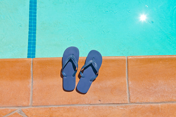 Un par de zapatillas azules en el borde de la piscina
. - Foto, imagen