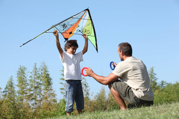 Vater und Sohn spielen mit einem Drachen - Foto, Bild