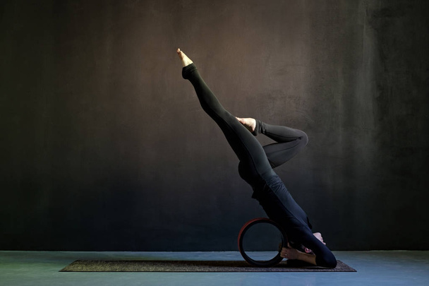 Vista lateral da jovem praticando ioga no estúdio
 - Foto, Imagem