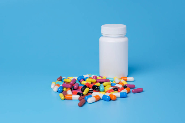 Medicine green, yellow and pink pills or capsules and white bott - Foto, Bild