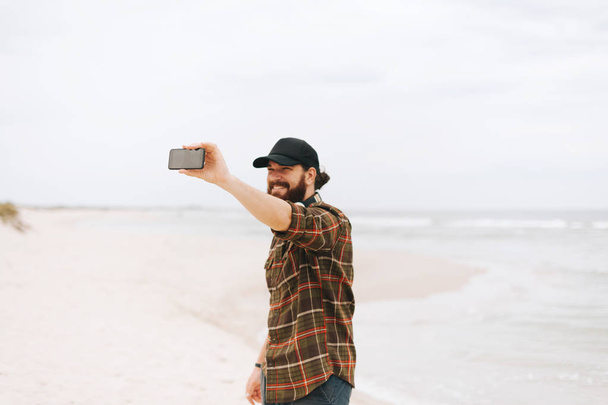 Portrait of a handsome bearded guy enjoying holinday and taking a selfie photo - 写真・画像