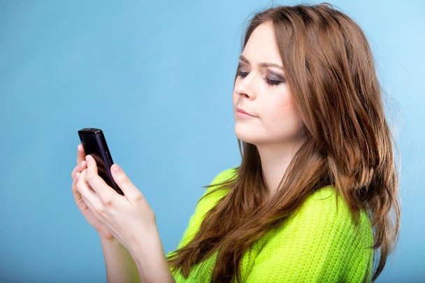 Nainen tekstailee näyttäen yllättyneeltä puhelimessa
 - Valokuva, kuva