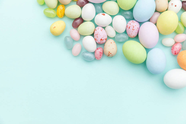 Happy Easter concept. Easter candy chocolate eggs and jellybean sweets isolated on trendy pastel blue background. Simple minimalism flat lay top view copy space - Fotó, kép