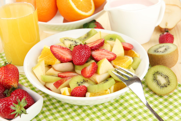 Useful fruit salad of fresh fruits and berries in bowl on napkin on wooden table close-up - Foto, imagen