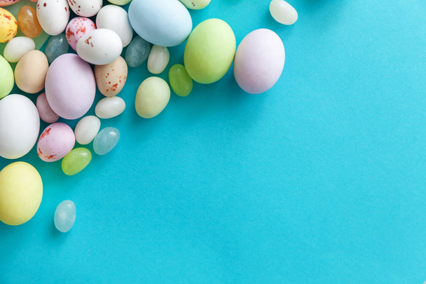 Счастливой Пасхи. Пасхальные конфеты шоколадные яйца и конфеты из медузы изолированы на модном пастельно-голубом фоне. Простой минимализм с плоским видом сверху
 - Фото, изображение