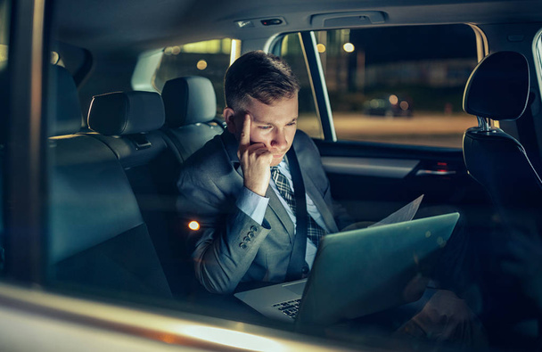businessman in moving car working on his laptop - 写真・画像