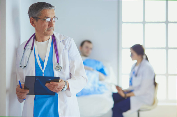Médico sosteniendo carpeta delante de un paciente y un médico - Foto, Imagen