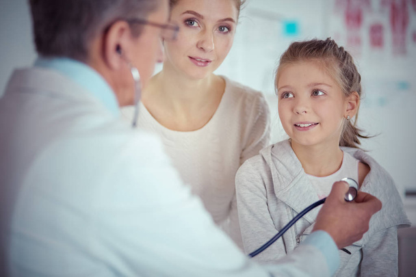 Girl and doctor with stethoscope listening to heartbeat - Foto, Imagen