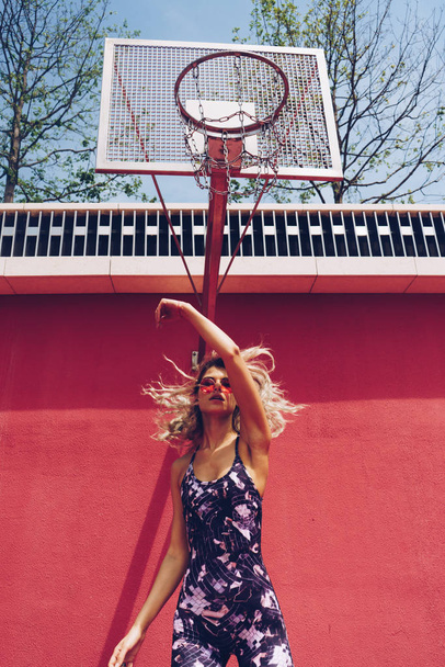 Fashionable girl athlete jumping and hitting the net of a basketball ring - Φωτογραφία, εικόνα