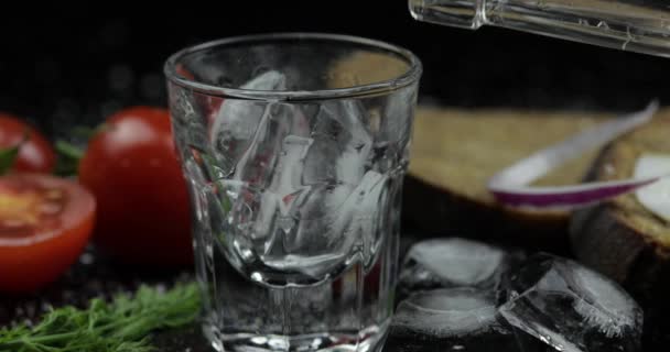 Nalijte alkohol vodku z láhve v střílené sklenici. Povrch s občerstvením - Záběry, video
