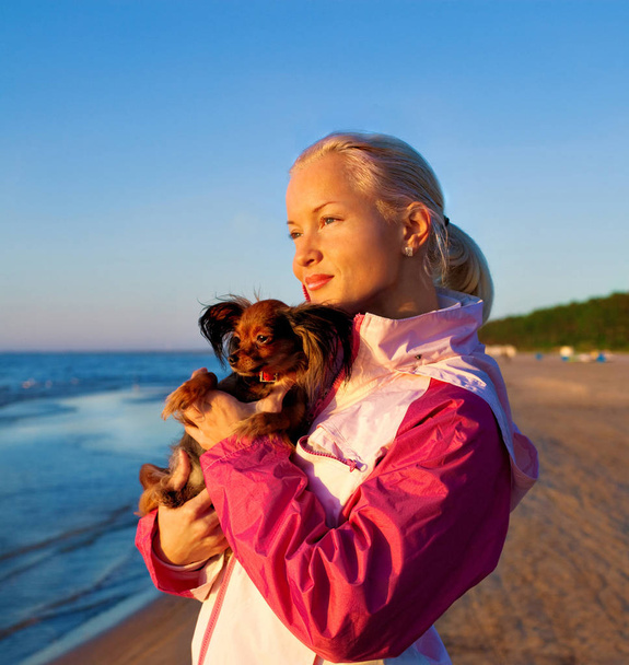 Mujer joven con su perro en una playa
 - Foto, imagen