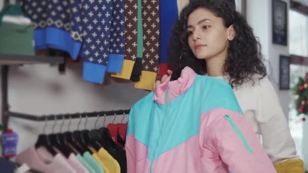 Lány választás két darab ruhát egy boltban. - Felvétel, videó
