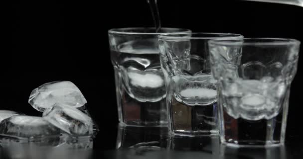 Giet drie schoten van wodka van een fles in glas. Zwarte achtergrond - Video