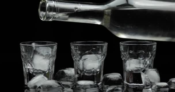 Öntött fel három lövés a vodka egy üveg üvegre. Fekete háttér - Felvétel, videó