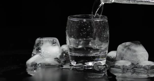 Verter un trago de vodka de una botella en un vaso. Fondo negro
 - Metraje, vídeo