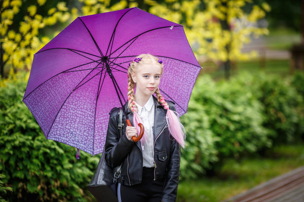 close up portrait of little beautiful stylish kid girl with an umbrella in the rain on park - Foto, imagen