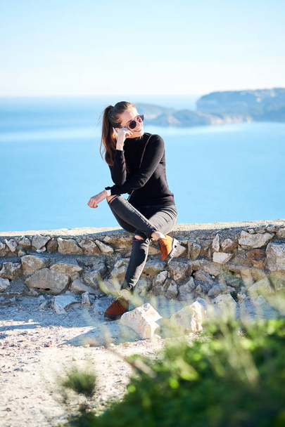Young woman is enjoying nature with panoramic sea view from a cliff. - Foto, imagen