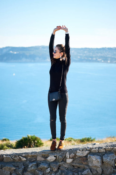 Young woman is enjoying nature with panoramic sea view from a cliff. - Foto, Imagem