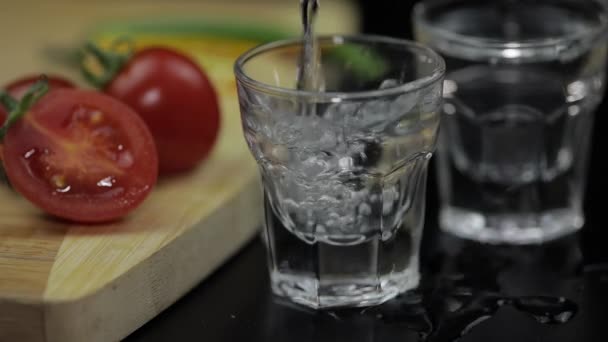 Versi la vodka di bevanda di alcool da una bottiglia in bicchierino. Superficie con snack
 - Filmati, video