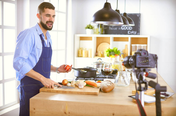 Hombre sosteniendo bolsa de papel llena de comestibles en el fondo de la cocina. Compras y concepto de comida saludable - Foto, Imagen