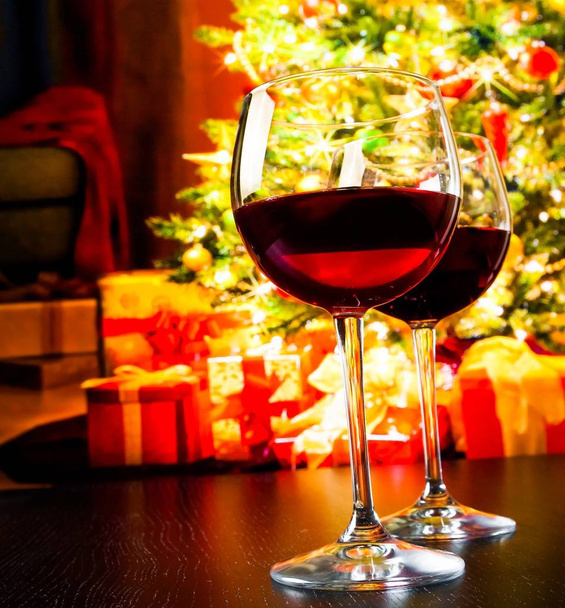 two red wine glasses against christmas tree background, christmas atmosphere - Foto, Imagem