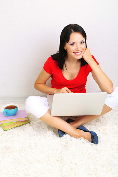 Beautiful young woman sitting with notebook in room - Photo, Image