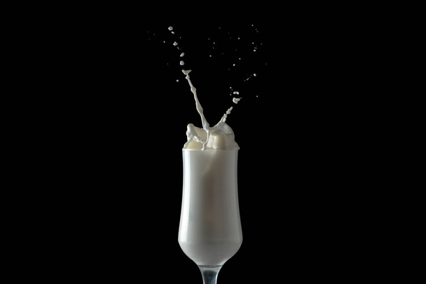 Melk Shake spatten van een glas. Geïsoleerde afbeelding op zwarte achtergrond. - Foto, afbeelding