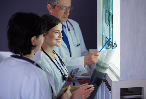 Bir grup doktor bir klinikte röntgenleri inceliyor, teşhis koymayı düşünüyorlar. - Fotoğraf, Görsel