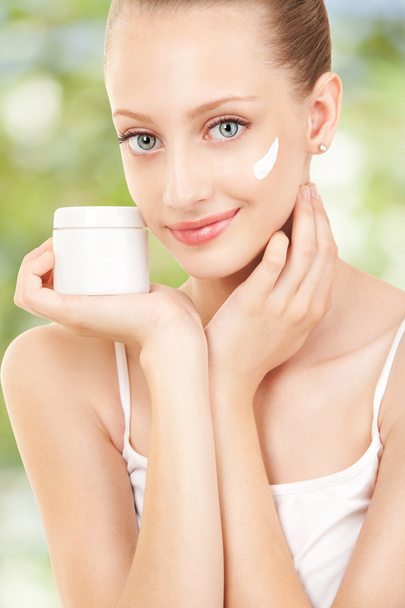 Cute woman applying cream to her face - Фото, изображение