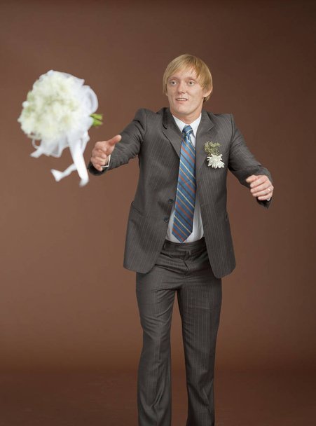 The groom catches a flying bouquet on a brown background - 写真・画像