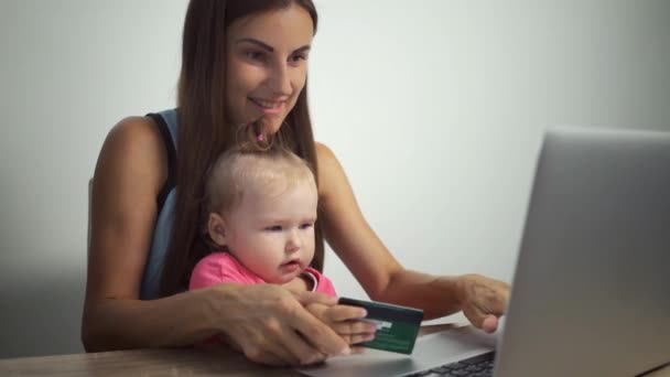 Compras concepto en línea. Mujer e hija sosteniendo una tarjeta de crédito y utilizando un ordenador portátil. mujer y niño pagan compras en línea
 - Metraje, vídeo