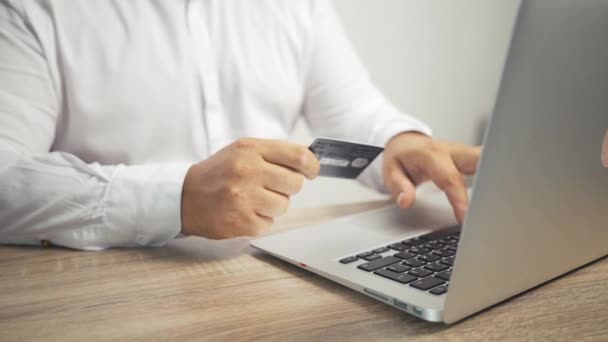 Концепция покупок онлайн. мужчина держит в руках кредитную карту и использует ноутбук
.  - Кадры, видео