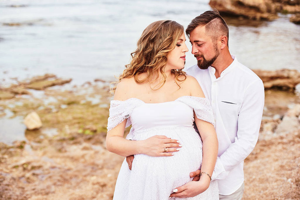 Portrait of a young pregnant woman posing with her husband on the beach - Photo, image