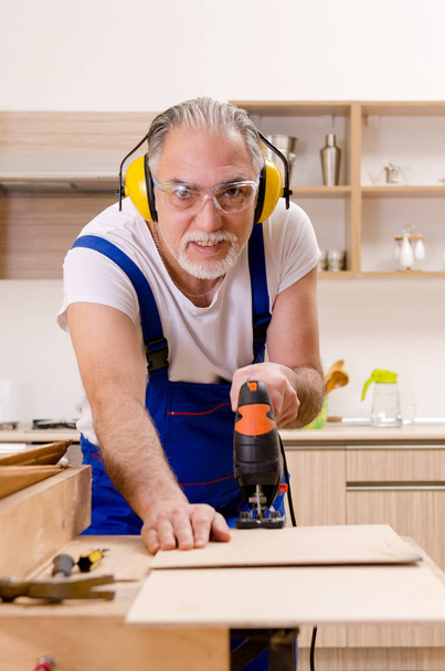 Contratista de edad reparador que trabaja en la cocina
  - Foto, Imagen