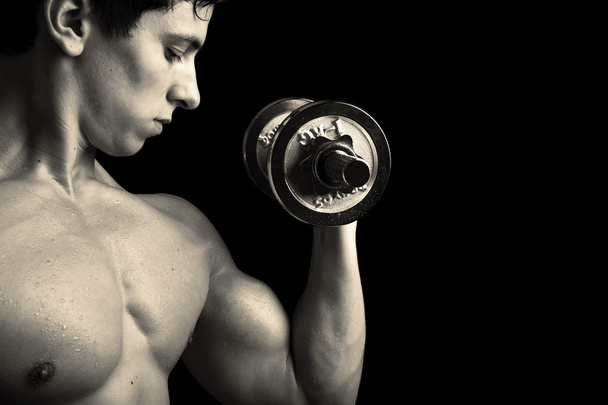 Closeup of a muscular young man lifting weights - Fotó, kép