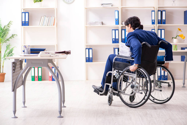 Junge männliche Angestellte im Rollstuhl bei der Arbeit im Büro  - Foto, Bild