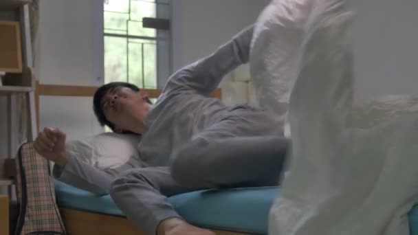 asiatischer Mann wacht morgens auf und sitzt mit Rückenschmerzen im Bett, 60 fps - Filmmaterial, Video