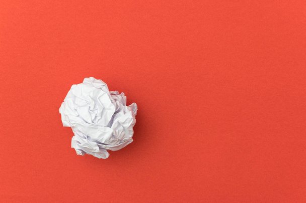 Τσαλακωμένη μπάλα χαρτιού σε κόκκινο φόντο για επιχειρηματική έννοια. - Φωτογραφία, εικόνα