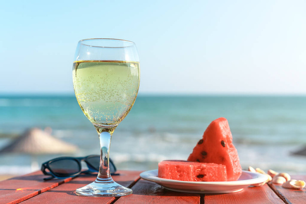 summer, a glass of champagne and fruit against the background of the sea - Фото, изображение