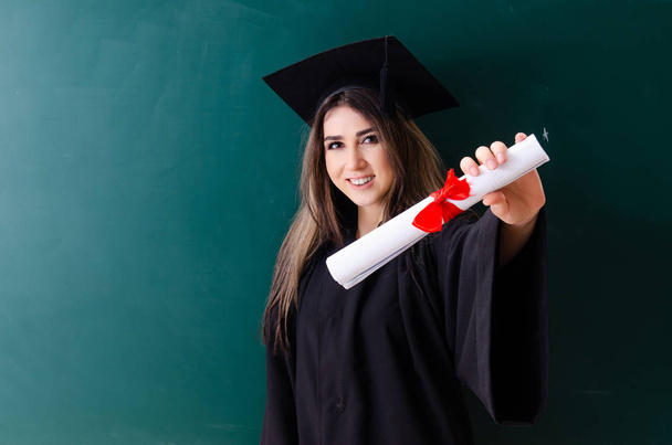 Estudiante graduada frente al tablero verde
  - Foto, imagen