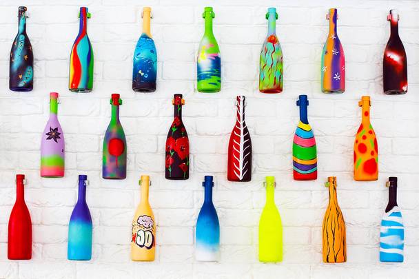 Яскраві декоративні пляшки, що звисають на білій цегляній стіні
 - Фото, зображення