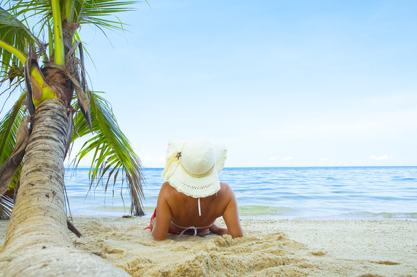 weergave van mooie vrouw loungen op tropisch strand in witte panama en bikini - Foto, afbeelding