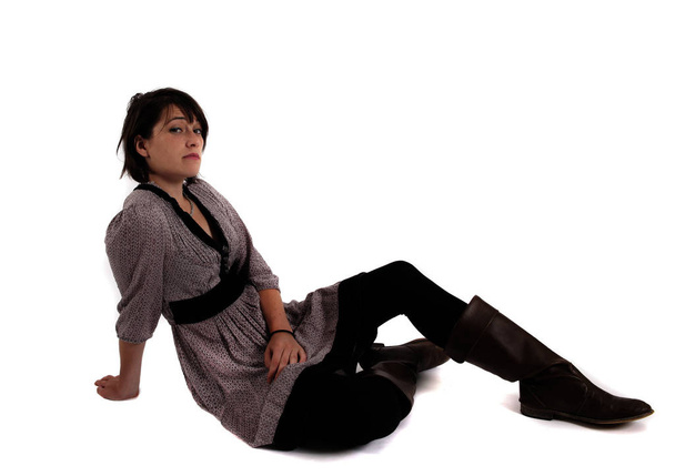 молодая брюнетка в платье сидит на земле с сапогами
 - Фото, изображение