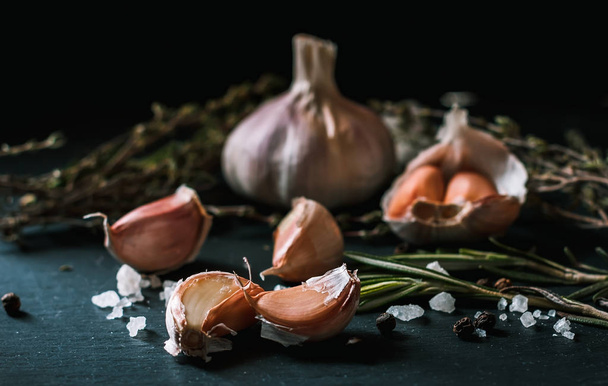 Garlic. Garlic on a black background. Nuts, cheese, rosemary and - Zdjęcie, obraz