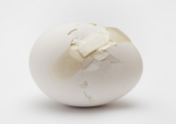 Тріснуте біле яйце з пластиковою штукатуркою
 - Фото, зображення