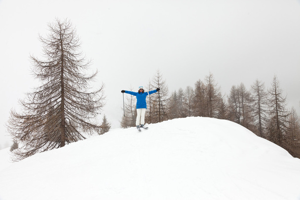 Happy ski woman standing in snow with pine trees. - Zdjęcie, obraz