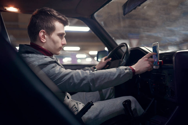 Side photo of man driver setting up navigator while sitting in car. - Fotografie, Obrázek