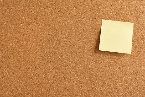 Σανίδα φελλού με ένα κίτρινο χαρτί κενό σημείωμα, κοντινό - Φωτογραφία, εικόνα