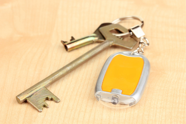 Ключі від будинку та брелок на дерев'яному фоні
 - Фото, зображення