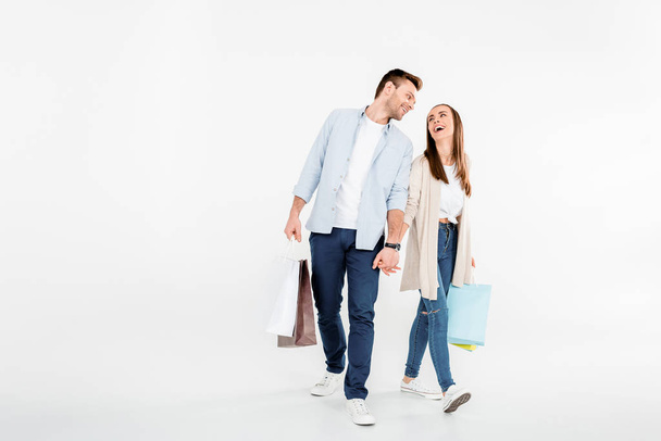 Happy young couple walking with shopping bags and looking at each other - Фото, зображення